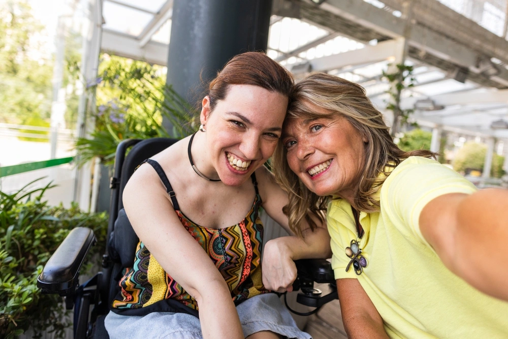 carer clicking selfie with a disabled women on wheelchair hanging out together