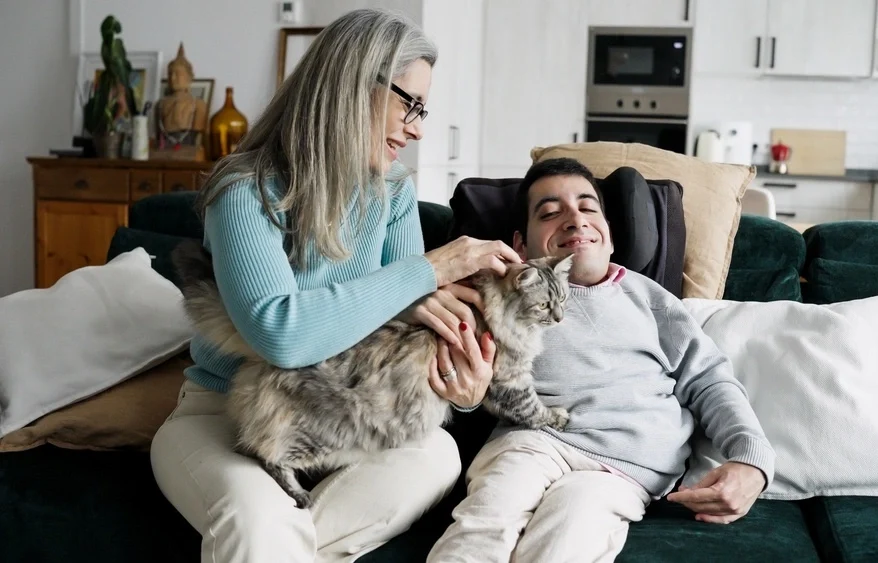 disability supported assistance petting a cat with a disabled men